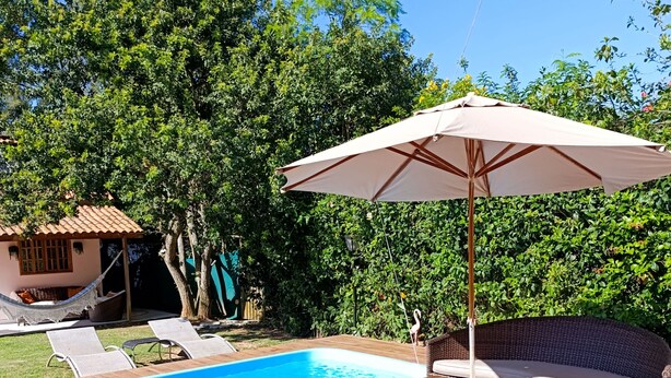A swimming pool with a wooden deck, wicker furniture, and a hammock. - Marina Guest House (Armação dos Búzios)