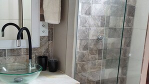 A bathroom with a glass shower enclosure, a sink with a glass basin, and a towel hanging on the wall. - Marina Guest House (Armação dos Búzios)