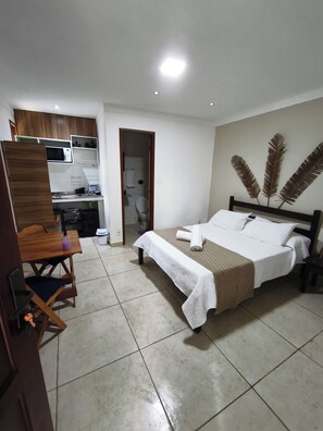 Ein Hotelzimmer mit Bett, Schreibtisch, Stuhl, einer Mikrowelle und einem Badezimmer.