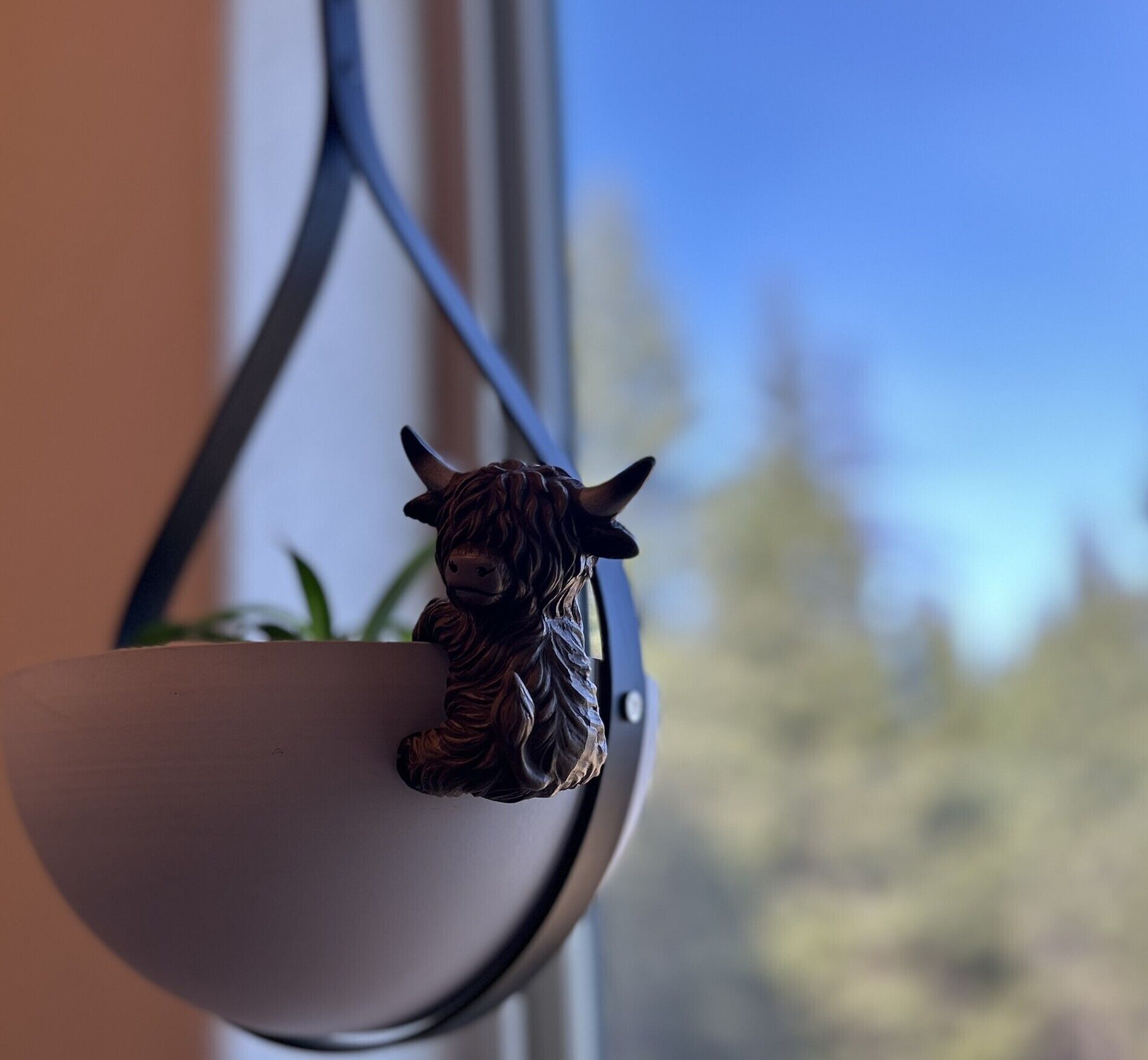 Una pequeña figura de llama en un macetero colgante.