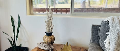 Ein Holztisch mit einer Vase, einer Fernbedienung und einer Topfpflanze.