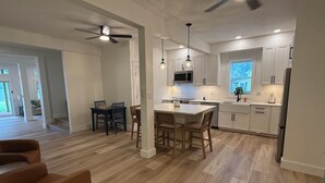 A modern kitchen with white cabinets, a central island, and pendant lighting. - Newly Renovated Family-Friendly 3-Bedroom Otisco Lake Home (Marietta)