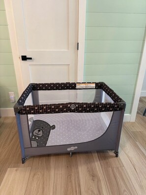 Una recinzione gioco per bambini con una parte superiore in rete e una base solida, posizionata su un pavimento in legno.