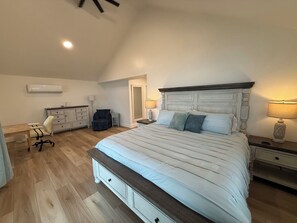 Ein Schlafzimmer mit einem großen Bett, einem Schminktisch, einem Schreibtisch und einer Klimaanlage.