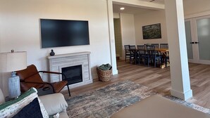 A living room with a fireplace, a television, and a dining area with chairs and a table. - Newly Renovated Family-Friendly 3-Bedroom Otisco Lake Home (Marietta)