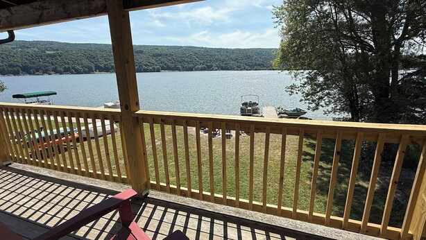 A wooden deck with a view of a lake and forest. - Newly Renovated Family-Friendly 3-Bedroom Otisco Lake Home (Marietta)