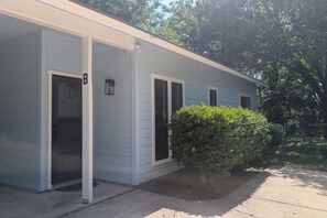 A single-story building with a garage door, a small porch, and a well-maintained hedge. - Montview cottage  Walk to Burnet Rd, Central ATX (Austin)