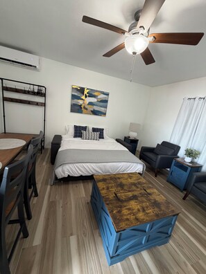 Ein modernes Schlafzimmer mit Bett, Schreibtisch, Stuhl, Deckenventilator und einem Bild an der Wand.