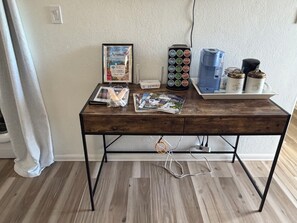 Un bureau en bois sur lequel on peut voir une pancarte d’accueil encadrée, une machine à café et divers objets.