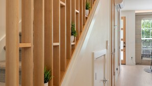Eine Holztreppe mit Blumentöpfen, die zu einem Raum mit einer Tür und einem Fenster führt.