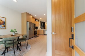 A modern kitchen with wooden cabinets, stainless steel appliances, and a dining area with a round table and chairs. - Your Portland Chapter Starts Here, 2 Ensuites (Portland)