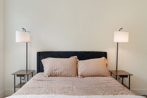 A bed with a quilted cover, two bedside tables with lamps, and a dark headboard. - Your Portland Chapter Starts Here, 2 Ensuites (Portland)