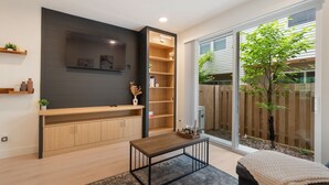 Eine moderne Küche mit Holzschränken, einem eingebauten Backofen und einem großen Fenster mit Blick auf einen Hinterhof.
