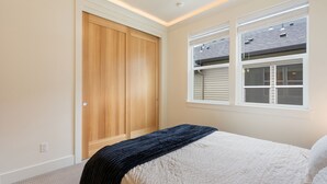 Ein Schlafzimmer mit einem Bett, einem Holzschrank und einem Fenster mit Jalousien.