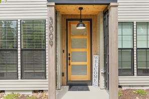 A house entrance with a wooden door, a welcome sign, and a black pendant light. - Your Portland Chapter Starts Here, 2 Ensuites (Portland)
