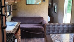 Eine kompakte Küchenzeile in einem Wohnmobil, mit Holdekor-Schränken, einem eingebauten Kochfeld und einer Karte an der Wand.