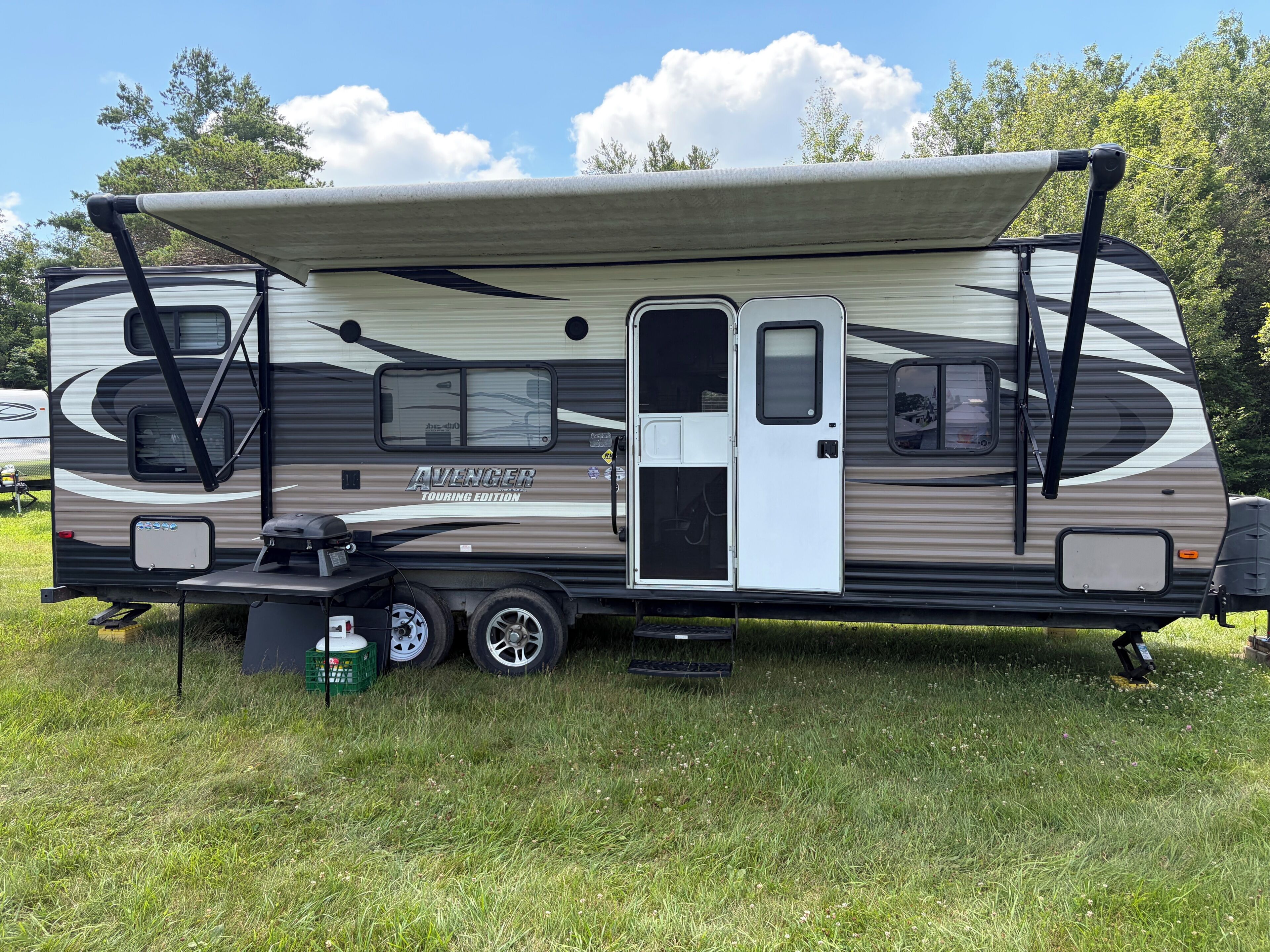 Un camper da turismo con frontale coperto, porta scorrevole e area barbecue.