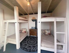 A bunk bed room with a ladder, a small wooden dresser, and a circular patterned rug.