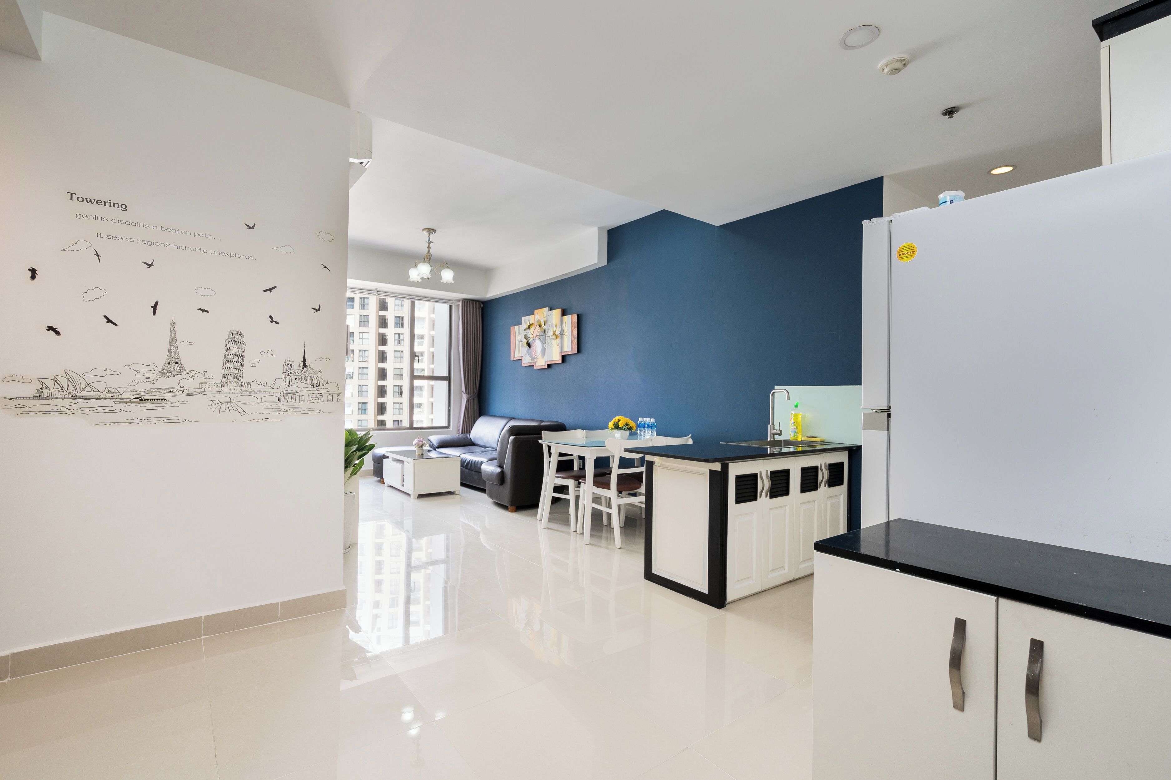 A modern kitchen with a built-in refrigerator, a dining area with a table and chairs, and a living room with a sofa and a coffee table.