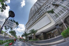 Un edificio moderno con una torre destacada, un cartel que indica un estacionamiento y una entrada bien cuidada con escalones que conducen a la entrada principal.