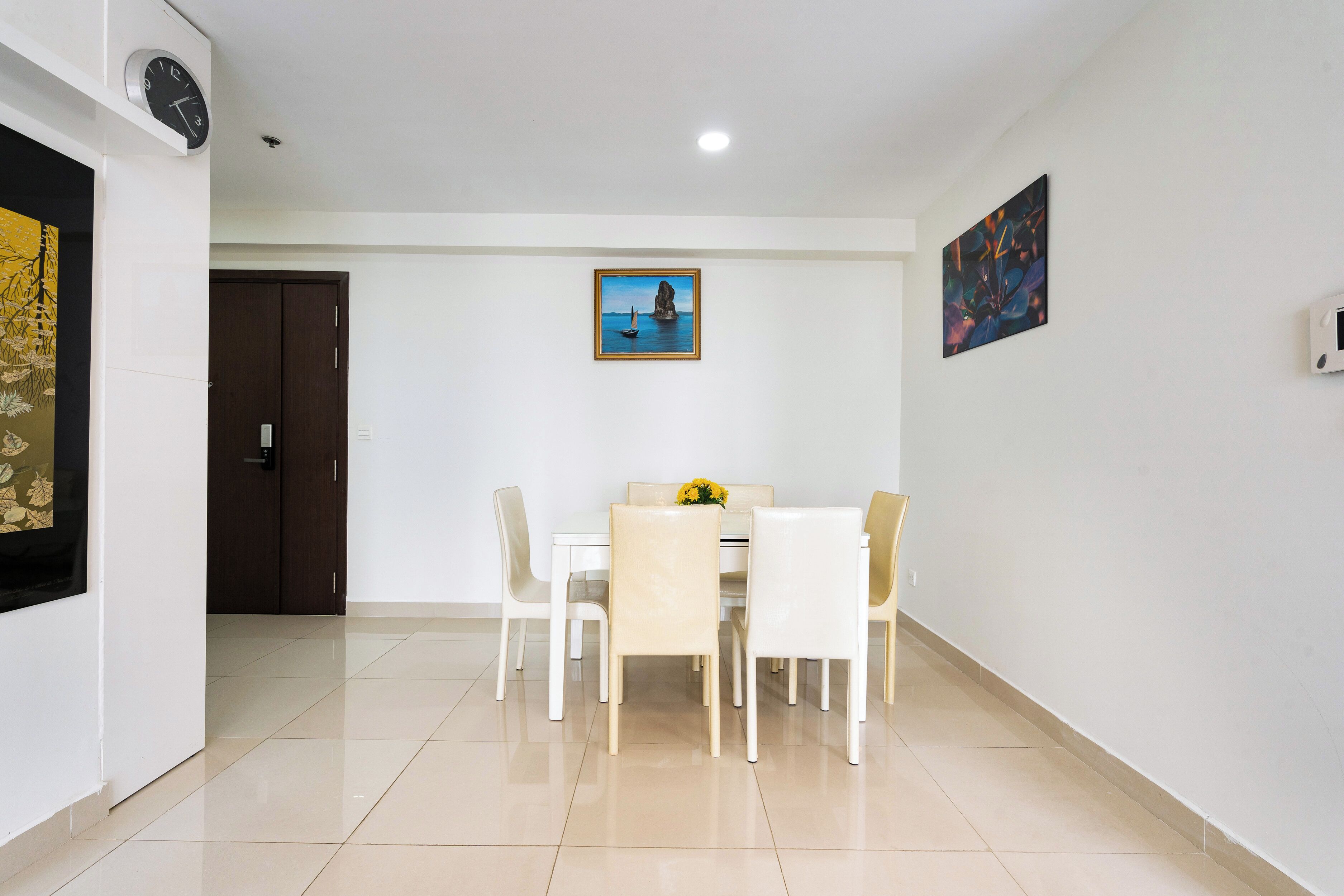 A dining area with a table and chairs, a painting on the wall, and a door.