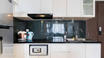 A modern kitchen with a digital inverter microwave, a rice cooker, and a coffee maker.