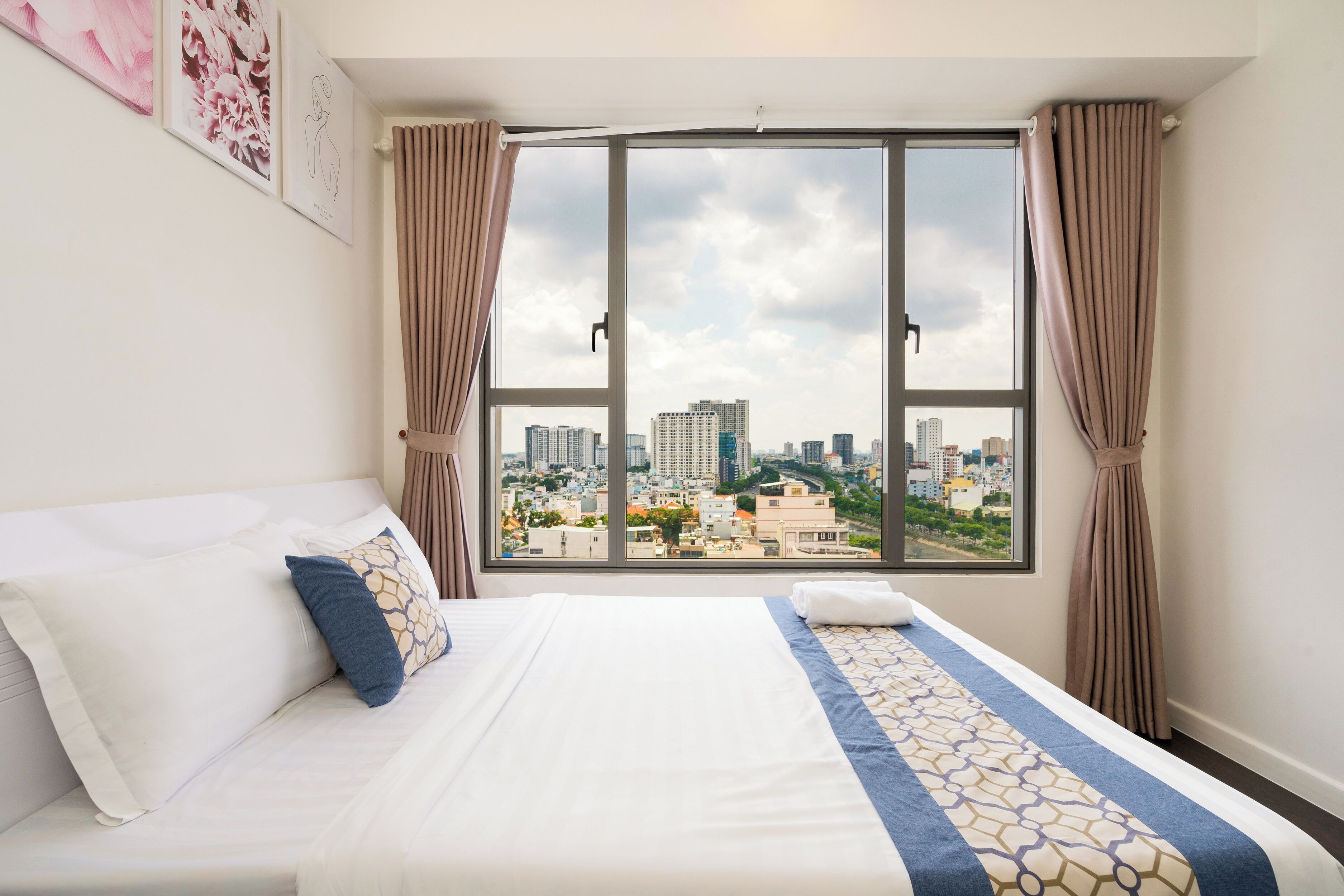 Ein Hotelzimmer mit großem Fenster, einem Bett mit weißen Leinen und Blick auf eine Stadtlandschaft.