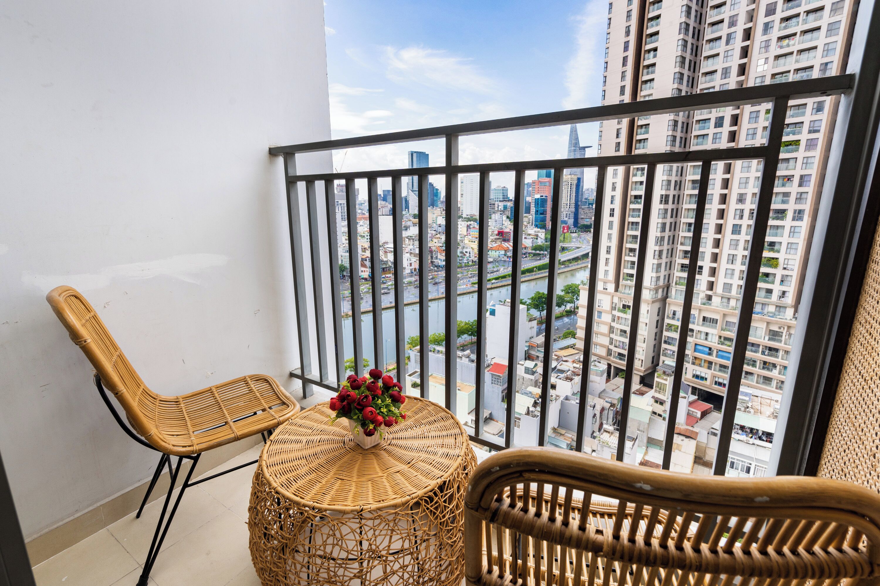 A balcony with wicker furniture and a view of a cityscape.