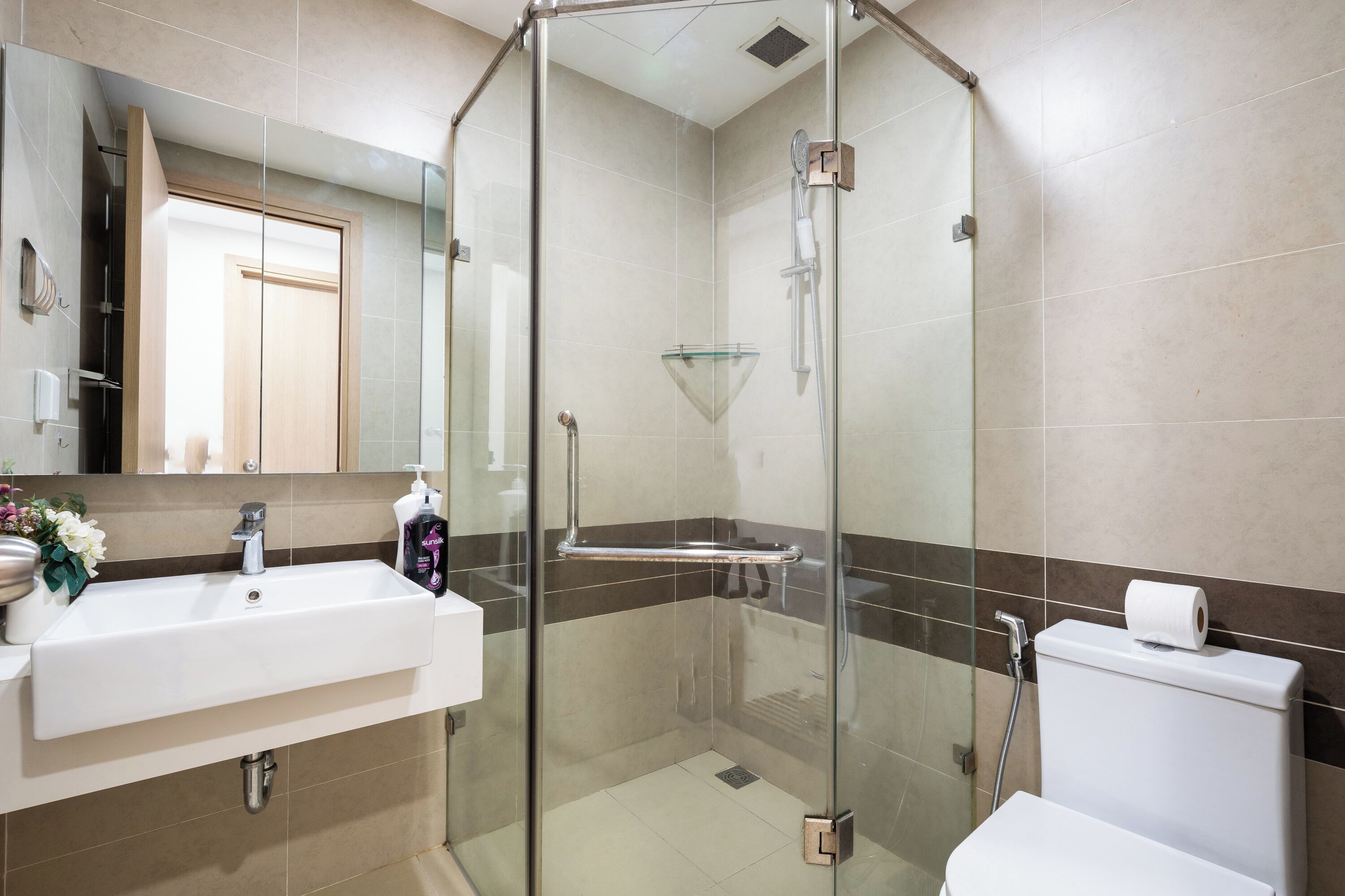 A modern bathroom with a glass-enclosed shower, a sink, and a toilet.