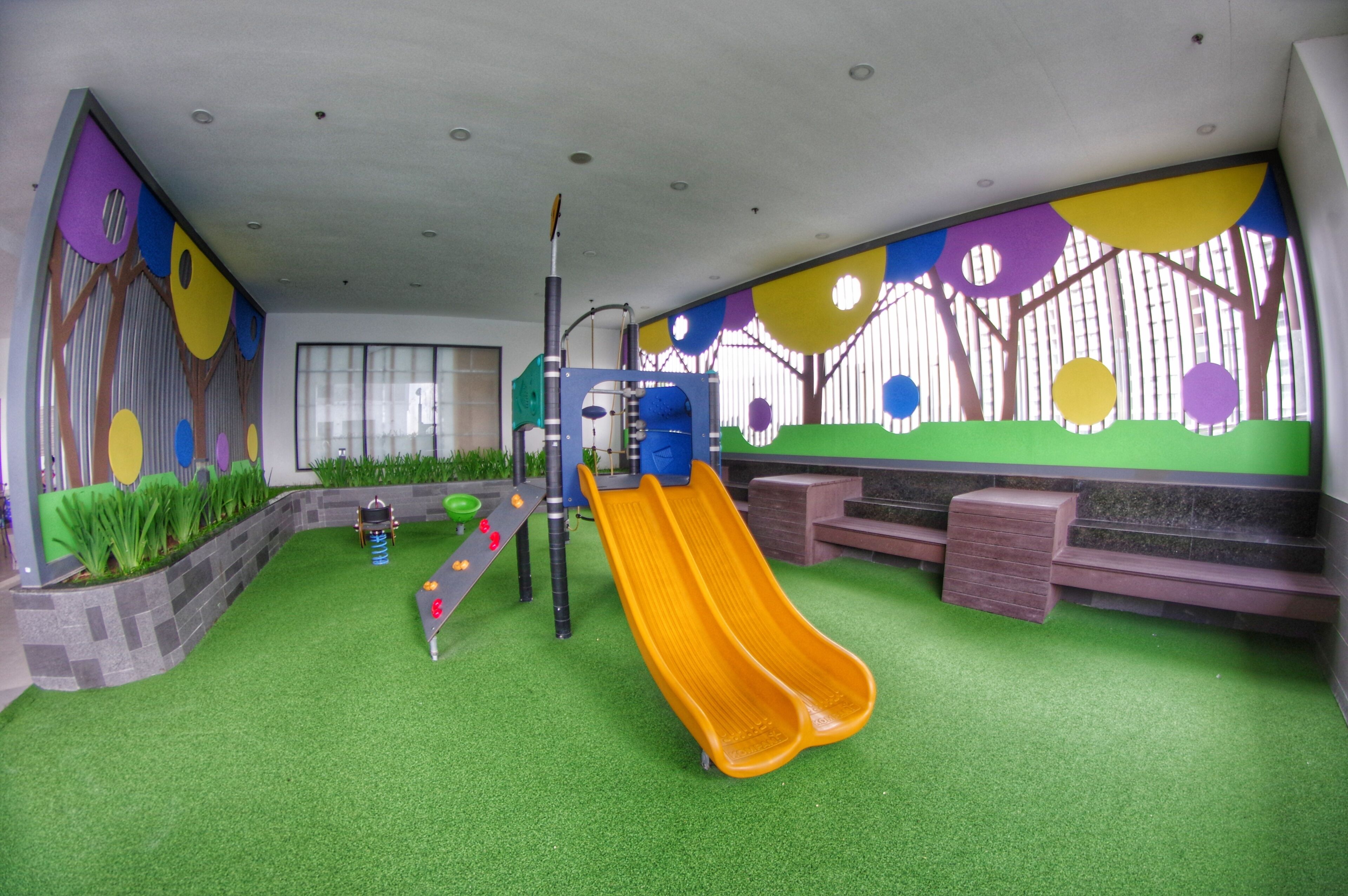 Uma área de recreação infantil com escorrega, estruturas de escalada e um mural na parede.