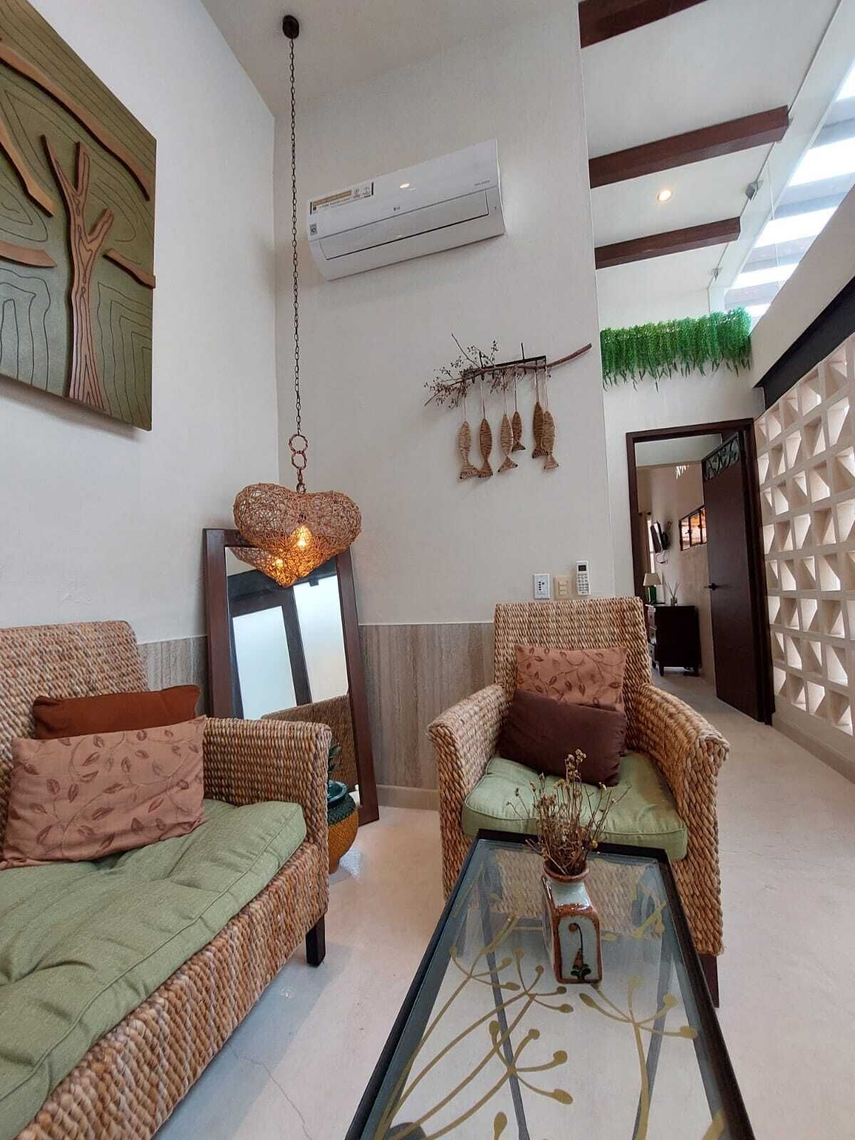 Ein modernes Wohnzimmer mit Rattanmöbeln, einem Glastisch und einer Wandklimaanlage.