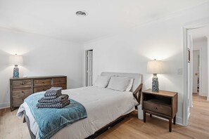 Ein Schlafzimmer mit Bett, Nachttischen, einem Schminktisch und einer Tür.