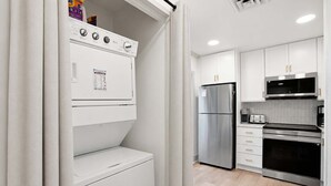 A compact kitchen with a built-in washer and dryer, stainless steel appliances, and white cabinetry. - 3BR New Renovation, with pool, tennis, trolley! (Bethany Beach)