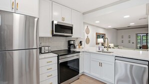 A modern kitchen with stainless steel appliances, white cabinetry, and a marble countertop. - 3BR New Renovation, with pool, tennis, trolley! (Bethany Beach)