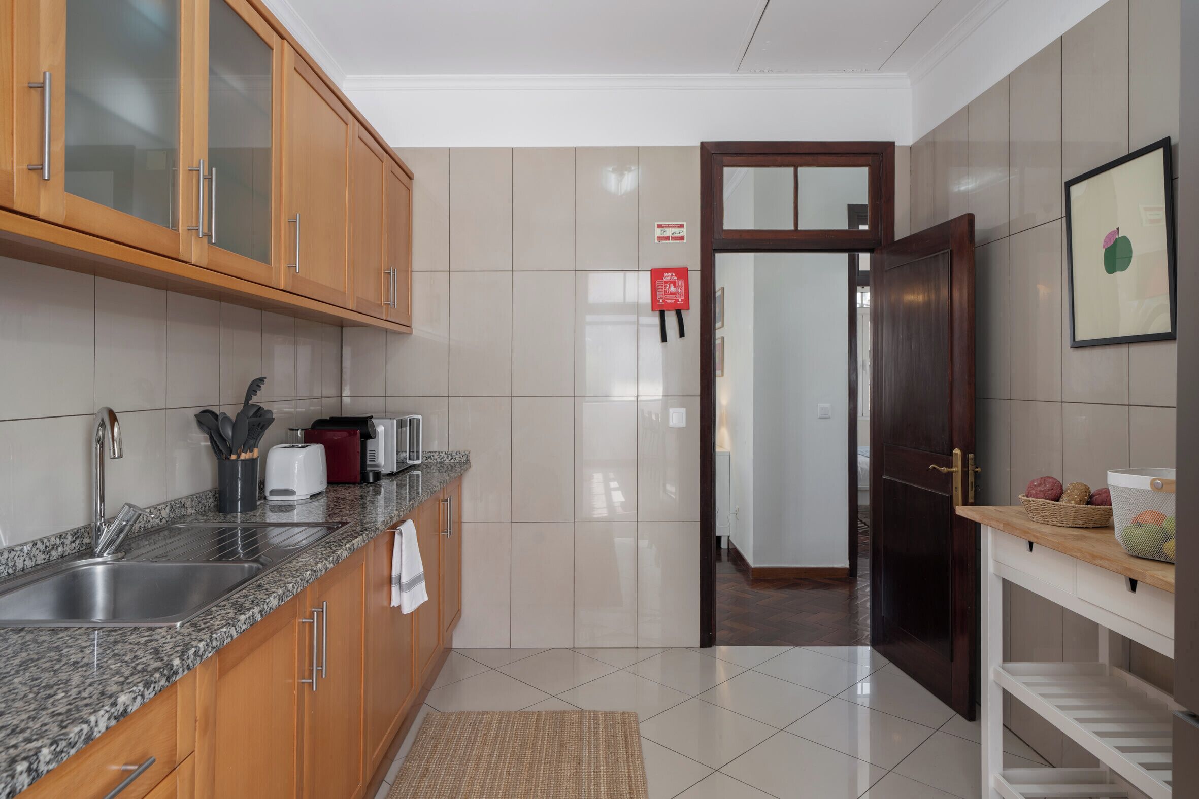 Una cocina moderna con armarios de madera, encimera de granito y pileta de acero inoxidable.
