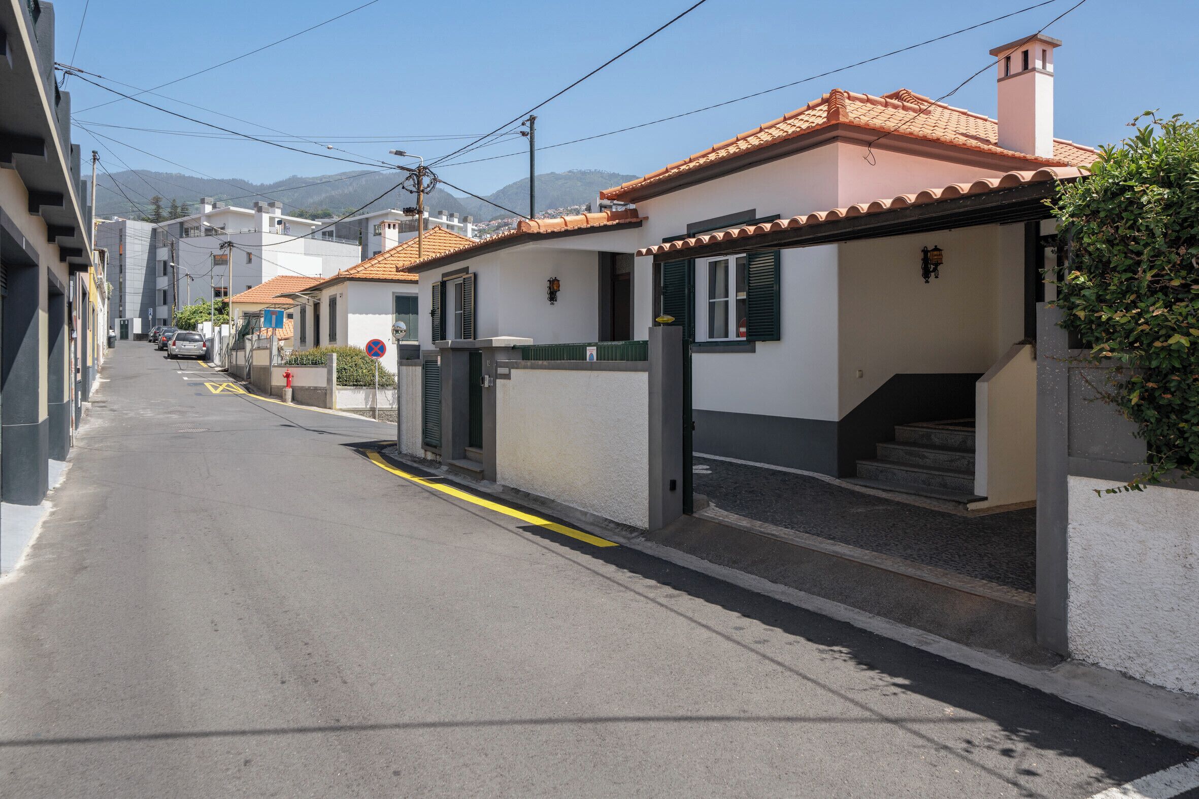 A residential street with houses, a clear sky, and a mountain in the background.