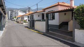 A residential street with houses, a clear sky, and a mountain in the background.