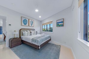 Ein modernes Schlafzimmer mit einem großen Bett, einem Nachttisch, einer Lampe und Kunstwerken an den Wänden.