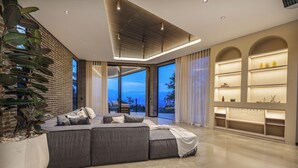 A modern living room with a sectional sofa, a large potted plant, and a view of the outdoors.