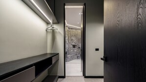 A modern bathroom with a dark wood door, a bench, and a tiled shower area.