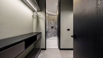 Un baño moderno con una puerta de madera oscura, un banco y una zona de ducha con azulejos.