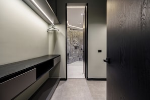 A modern bathroom with a dark wood door, a bench, and a tiled shower area.