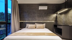 A modern hotel room with a large bed, a desk, and a view of the outdoors.