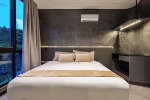 A modern hotel room with a large bed, a desk, and a view of the outdoors.