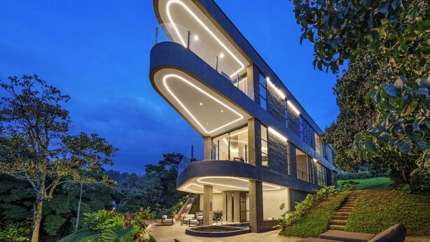 Een modern meerijlaarig gebouw met een gebogen gevel en verlichte binnenzijde.