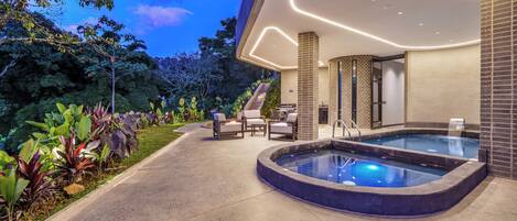 A modern outdoor pool area with a hot tub, seating, and a staircase leading to a covered area.