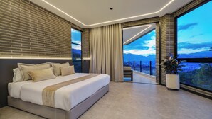 Een moderne slaapkamer met een groot bed, uitzicht op de stad en een balkon.