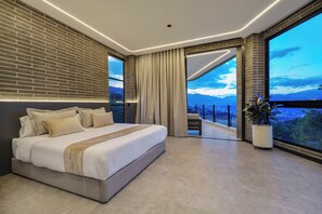 Un dormitorio moderno con una cama grande, vistas a la ciudad y un balcón.