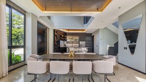 Een moderne keuken met inbouwapparatuur, een eethoek met een grote tafel en stoelen, en een uitzicht op het landschap door grote ramen.