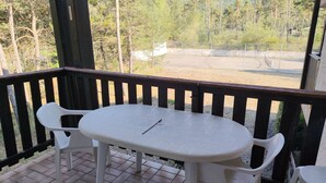 A covered outdoor seating area with a table and chairs, overlooking a mountainous landscape.